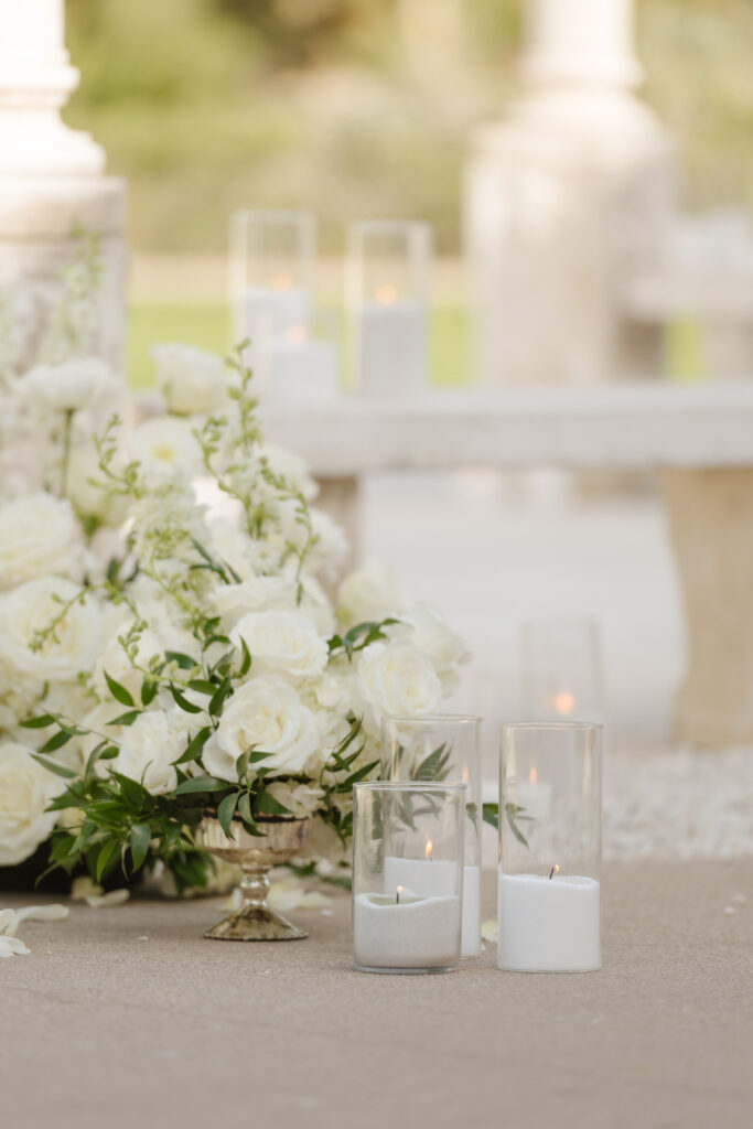 Lush white floral arrangement and hurricane candles at the proposal
