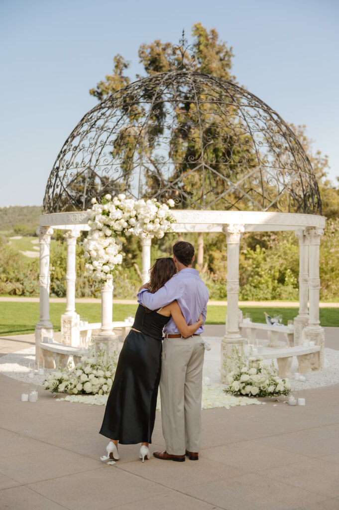 Couple hugging among white rose petals after the proposal