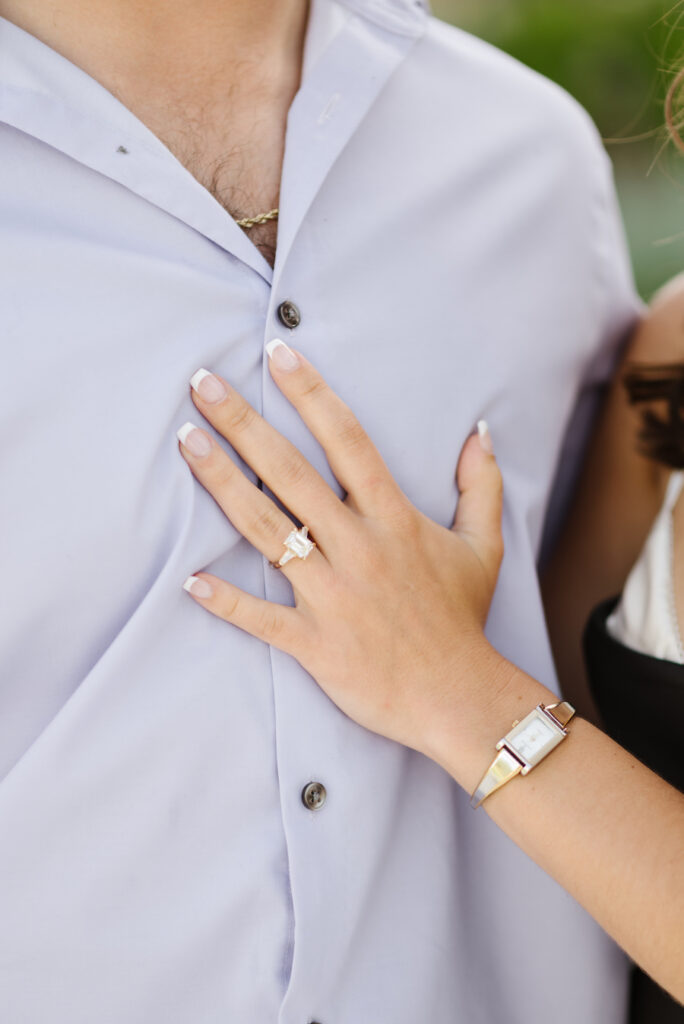 Close-up of her engagement ring as she rests her hand on his chest