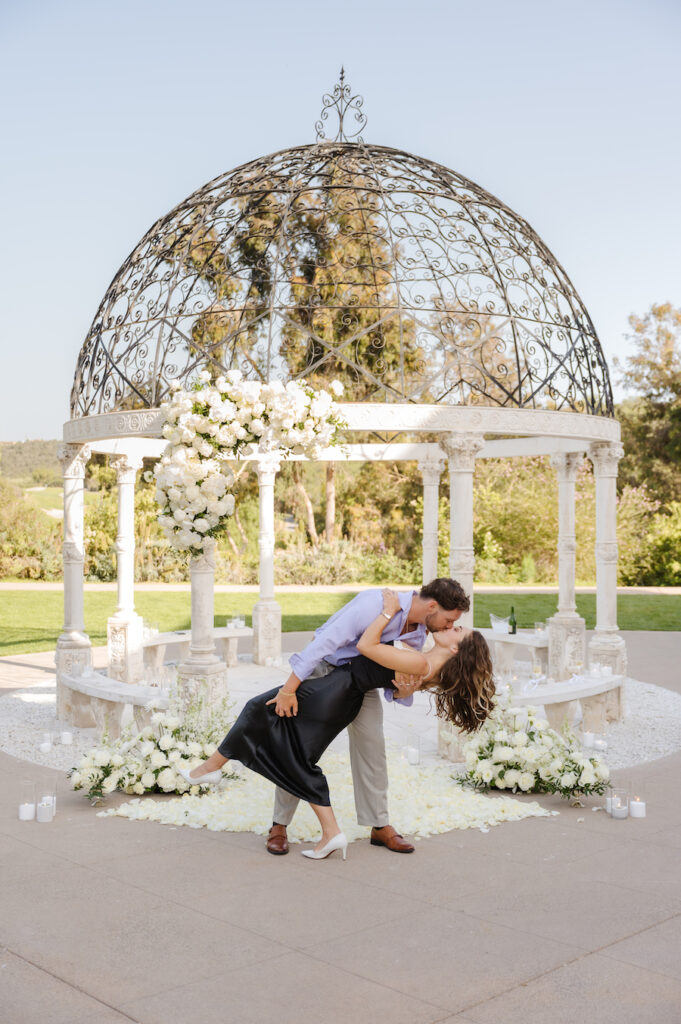 Man dipping her for a kiss beneath the white gazebo