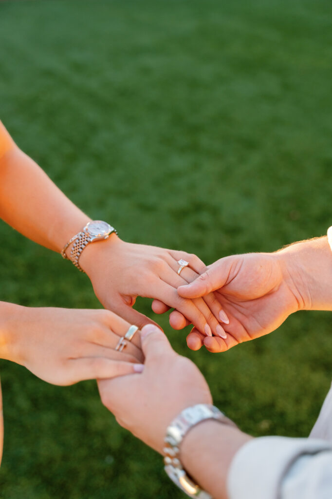 Close-up of the couple holding hands, showing her engagement ring
