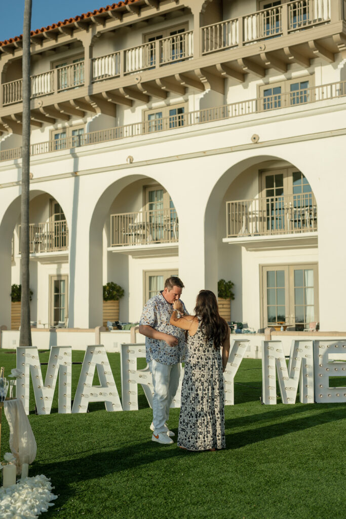 Couple embracing beside the MARRY ME marquee letters at The Ritz-Carlton, Laguna Niguel